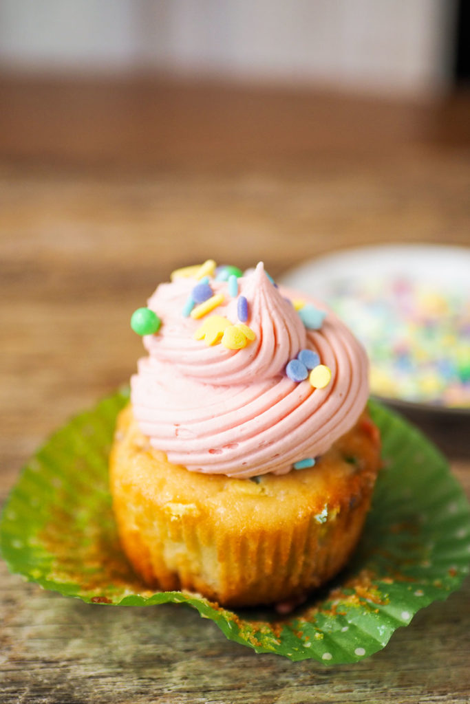 pretty cupcake with wrapper peeled away and pink frosting and sprinkles