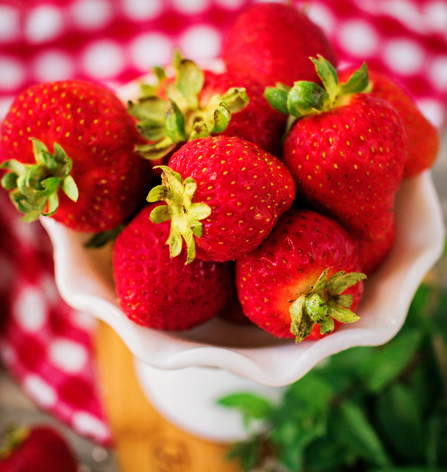 close up picture of red ripe strawberries in a vintage while bowl