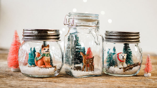 collection of three decorated mason jar crafts with woodland animals and bottle brush trees