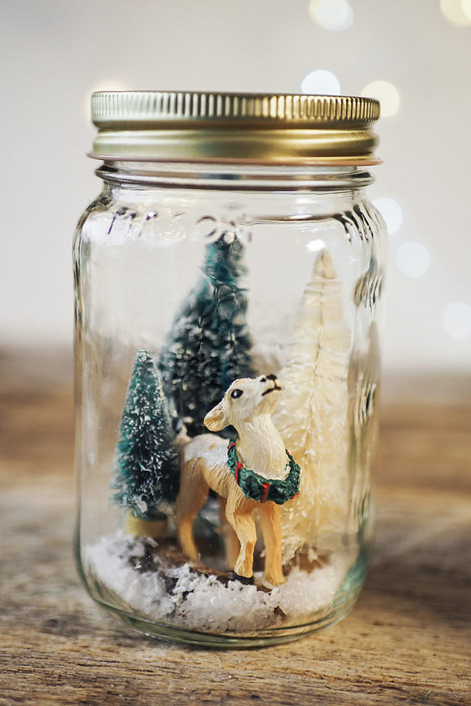 miniature deer and bottle brush trees in a mason jar