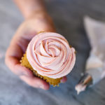 hand holding cupcake with frosting piped to look like a rose
