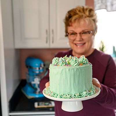 smiling woman holds a small layer cake