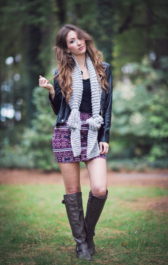 young woman wears long knitted scarf with ends knotted