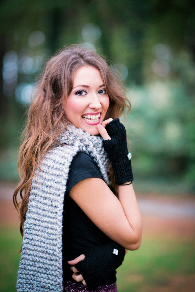 smiling young woman shows off a chunky knitted scarf