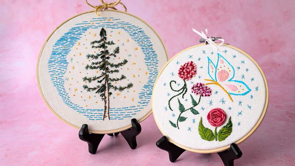 Two embroidery projects sitting side by side. One is a stitched pine trea and the other is a flower sampler with a butterfly