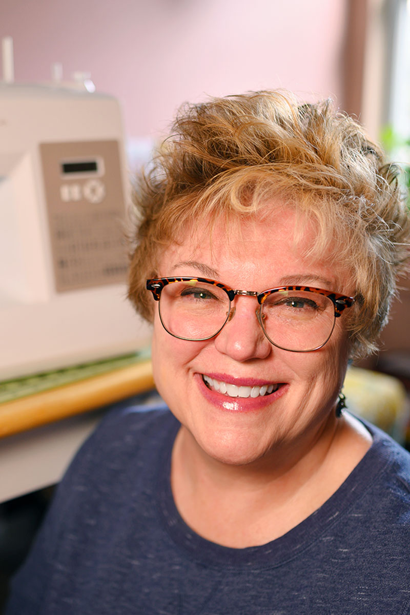 Smiling woman seated in front of a sewing machine