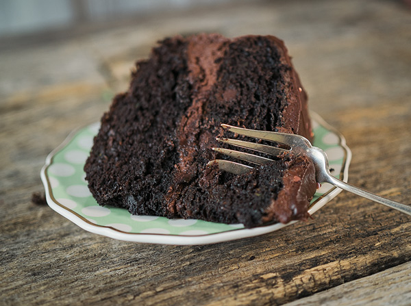 a slice of chocolate layer cake on a plate with a fork ready to take a bite