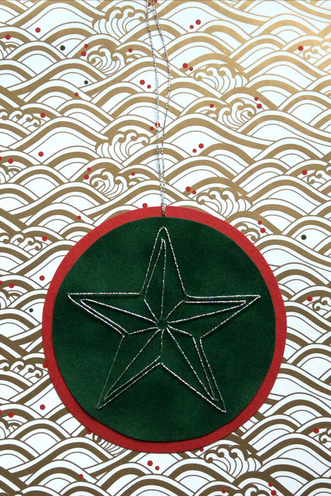 Round gift tage hand stitched on paper with red and green paper and a silver star