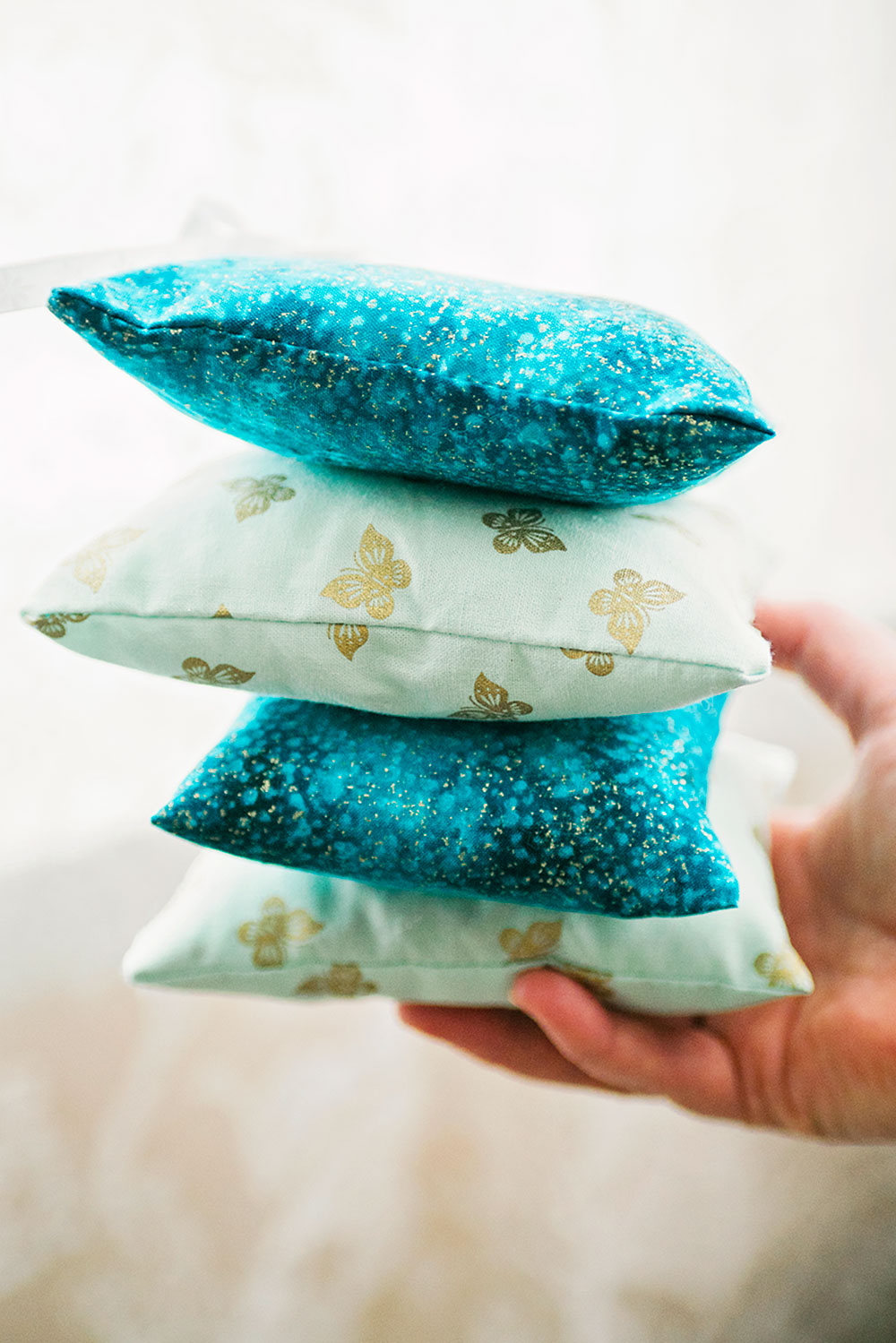 a hand balancing a stack of blue dream pillows
