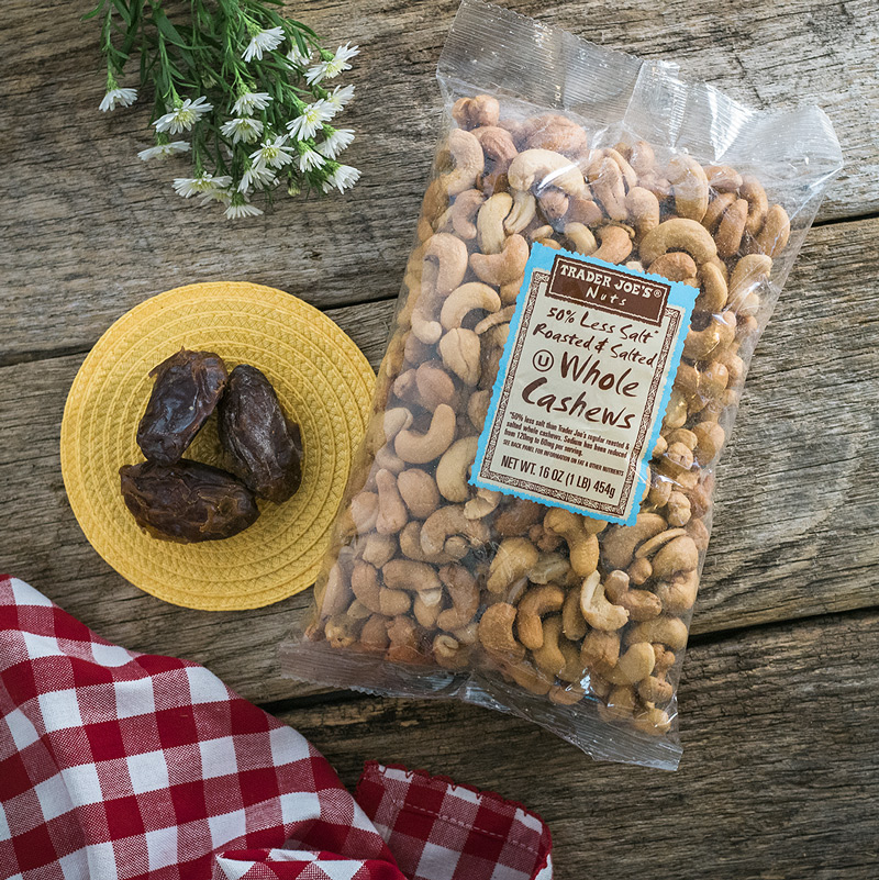 overhead view of a bag of roasted cashews from Trader Joe's and 3 medjool dates