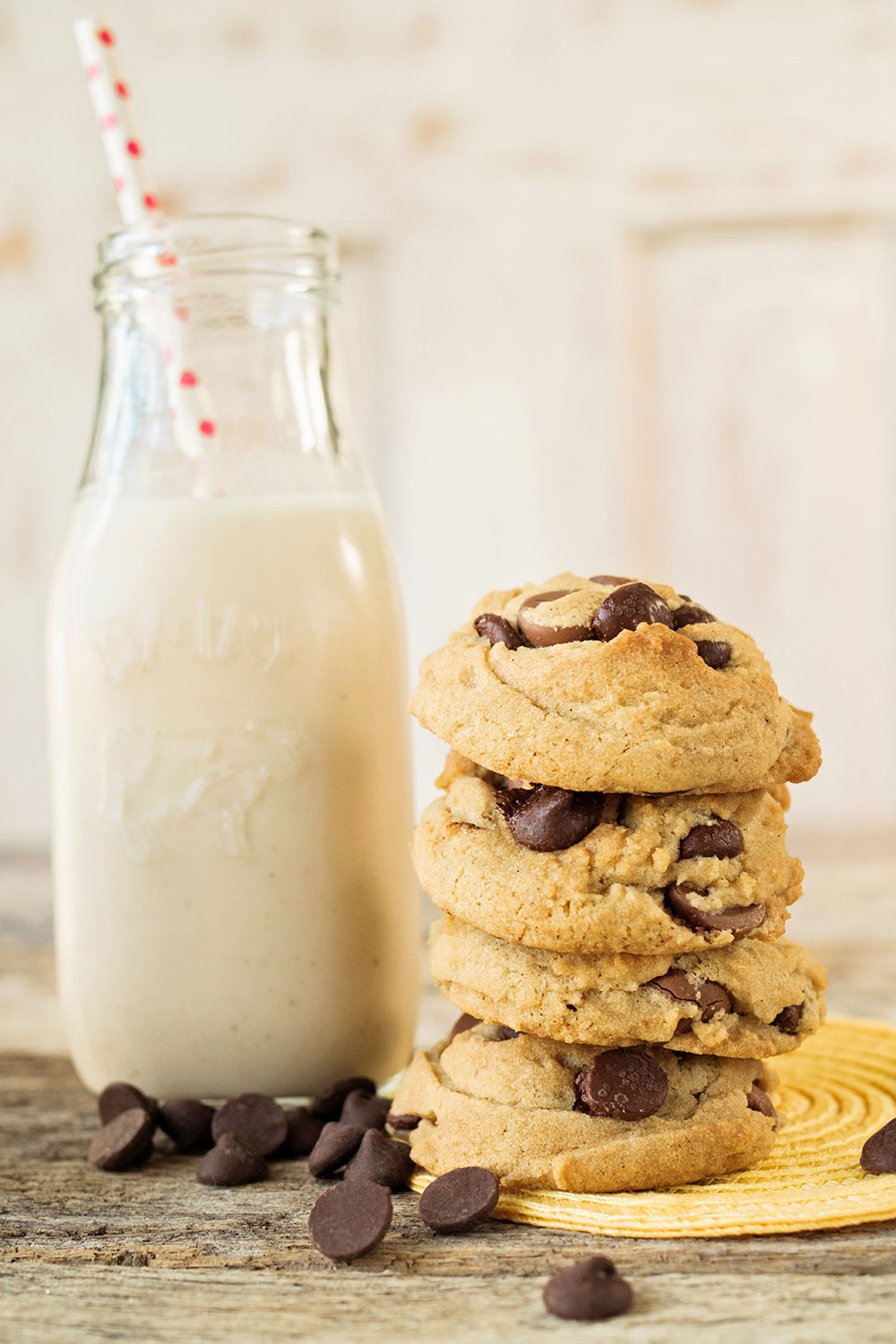 stack of 4 vegan chocolate chip cookies with a small milk bottle of cashew milk