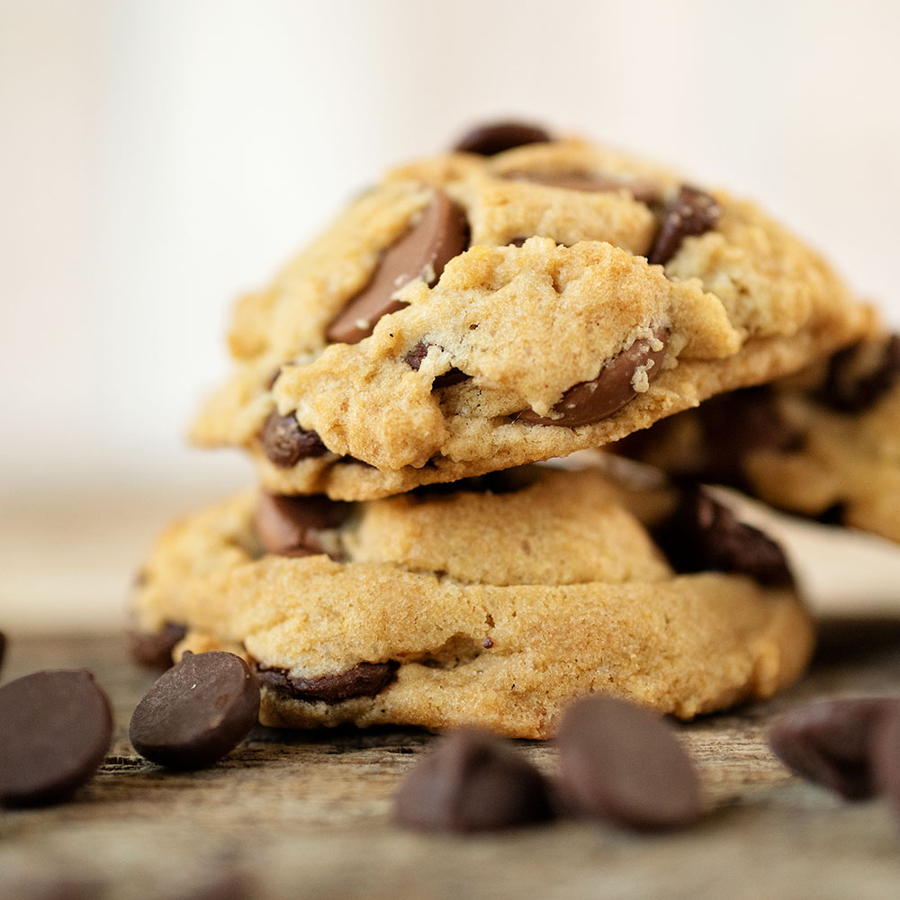 macro close up of two vegan chocolate chip cookies with chocolate chips scattered everywhere