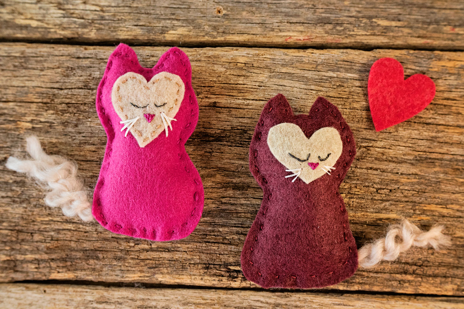 two hand sewn felt kittens together with a felt hear cut out
