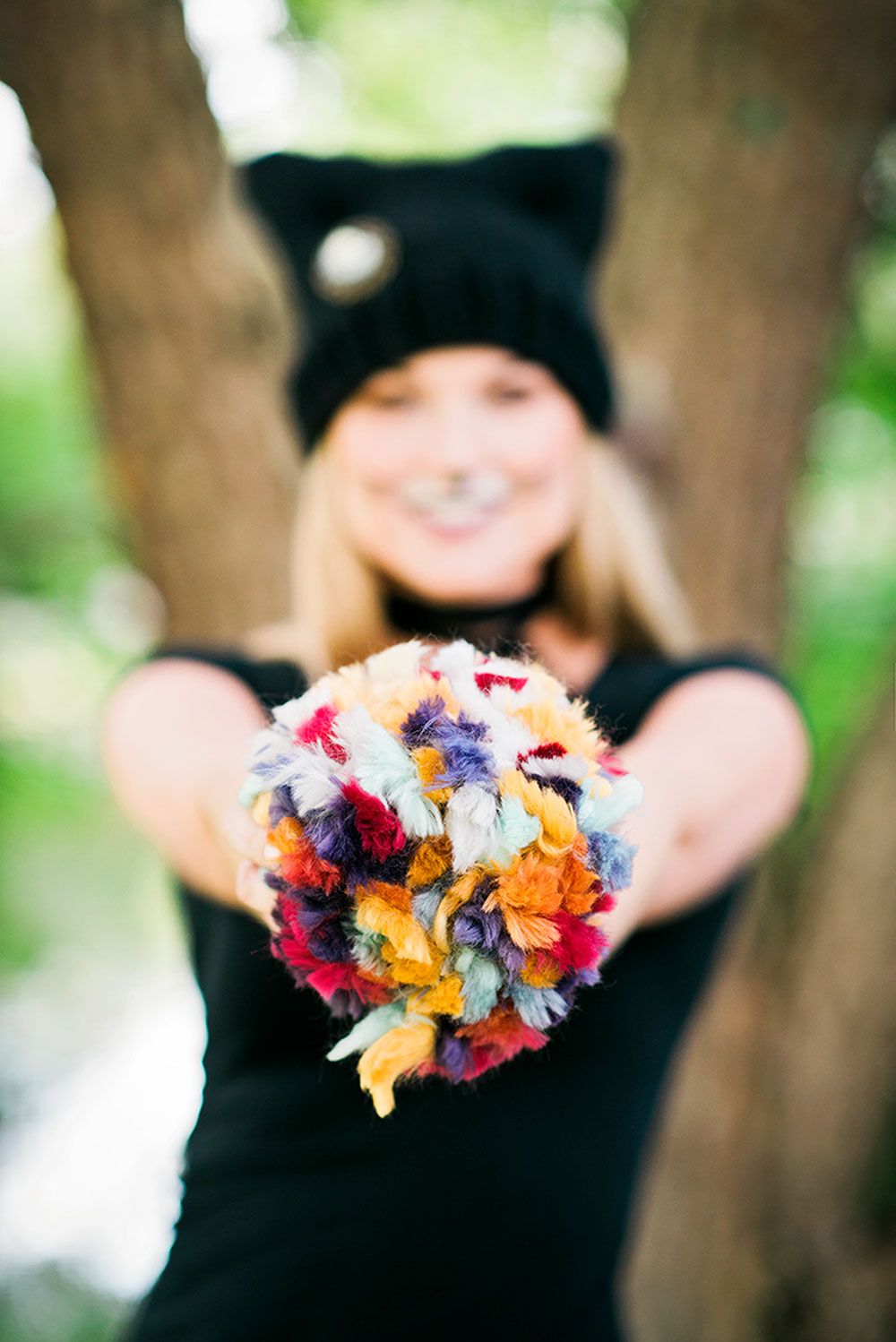 model holds jumbo multi colored pom pom in front of her