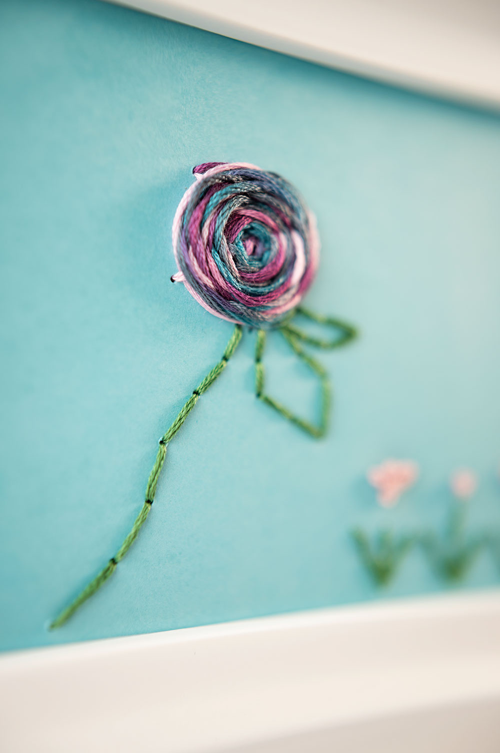 closeup view of the woven wheel rose and back stitch stem