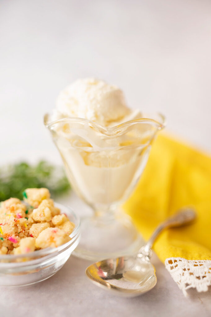 vintage glass dish with vanilla ice cream with yellow linen napkin and antique spoon