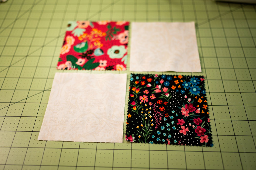 4 squares of fabric laying in 4 patch formation on a green cutting mat