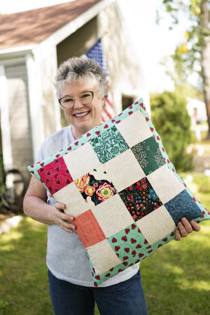 smiling woman hold an over sized patchwork pillow