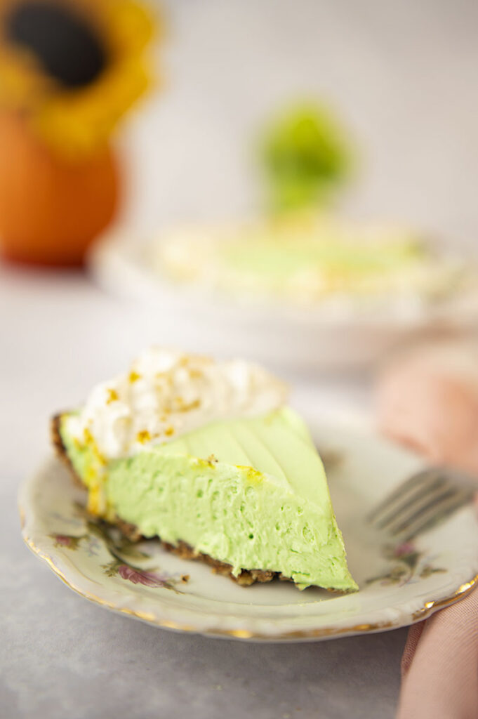 close up of a slice of key lime cheesecake on a vintage plate