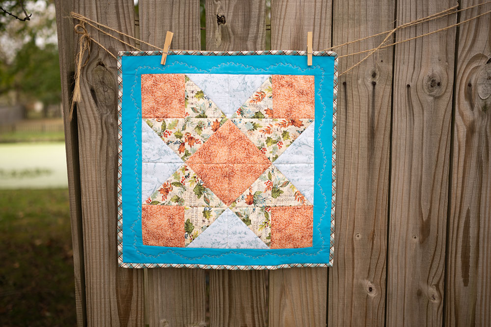 Ribbon quilt project displayed on a rustic fence