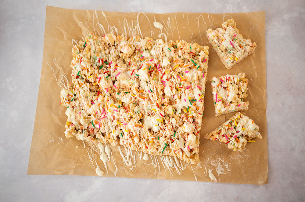 over head view of cut rice kripsies treats topped with white chocolate and sprinkles