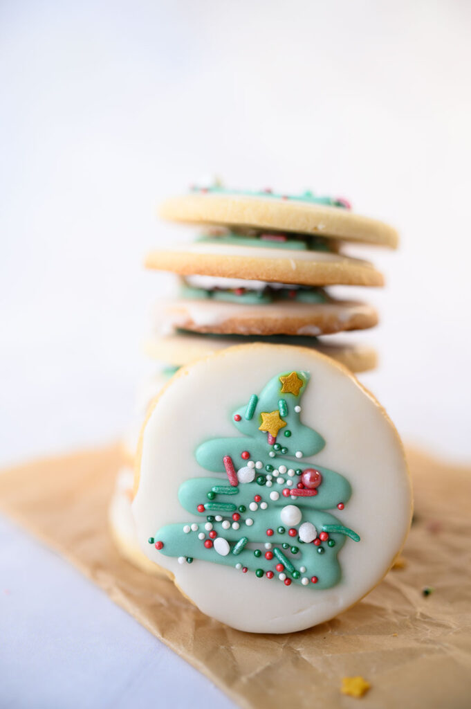 Closeup view of a round Christmas cookie decorated with a Christmas tree and sprinkles