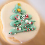 Closeup view of a round Christmas cookie decorated with a Christmas tree and sprinkles