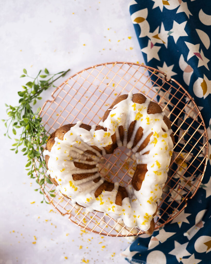 overhead view of a cake shaped like a heart with a white glaze and lemon zest decoration