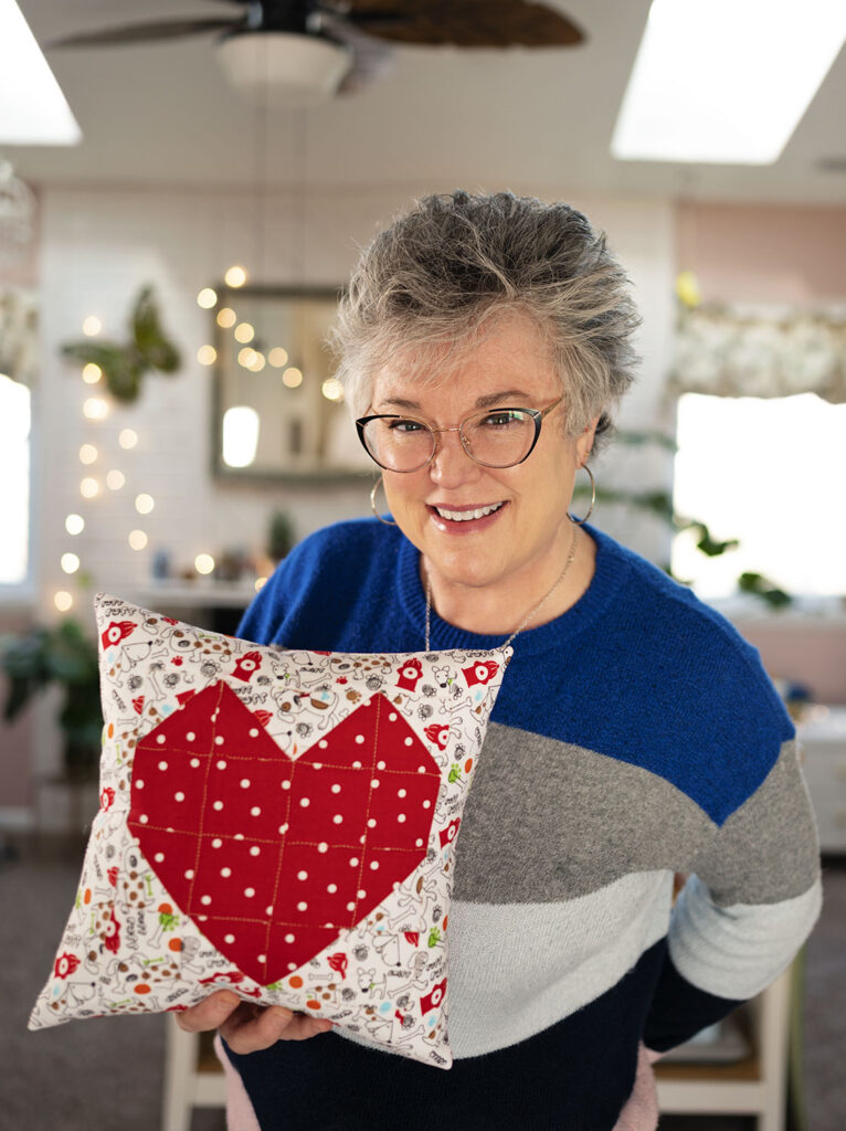 Smiling woman holds a quilted heart pillow