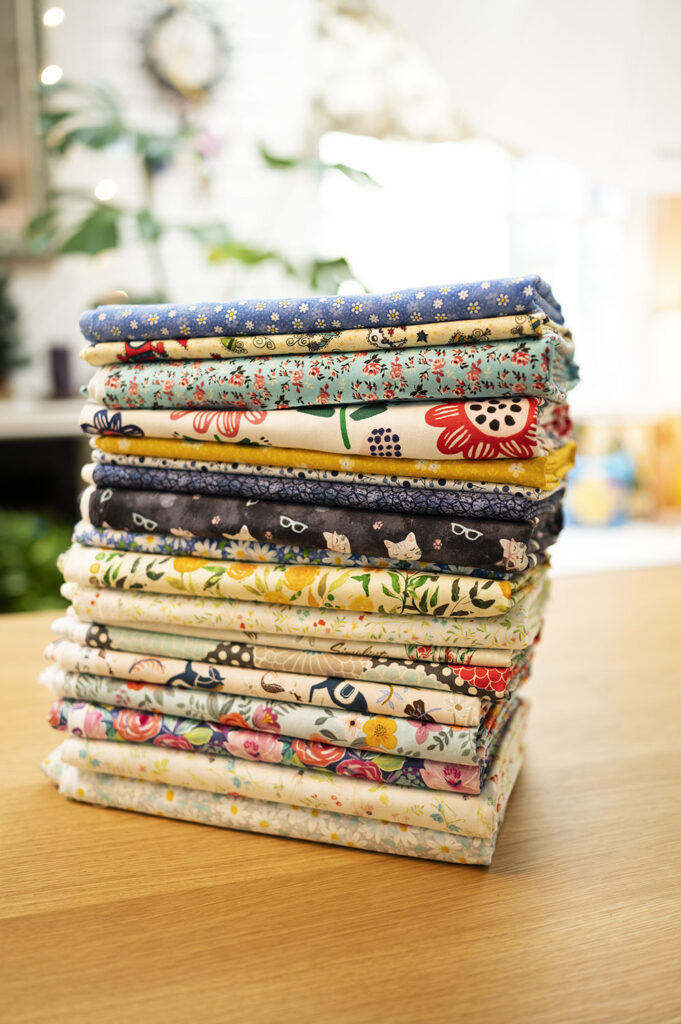 a tall stack of neatly folded fabrics on a wood countertop