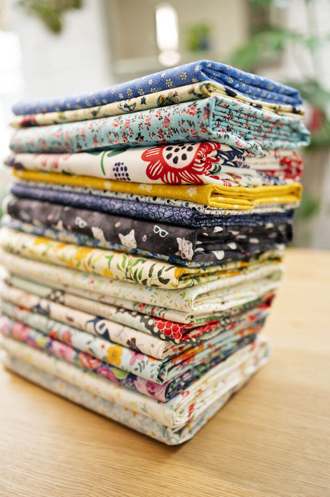 a tall stack of neatly folded fabrics on a wood countertop