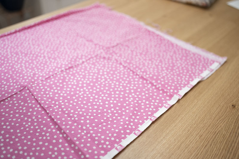 a large cut of pink polka dot fabric laying flat