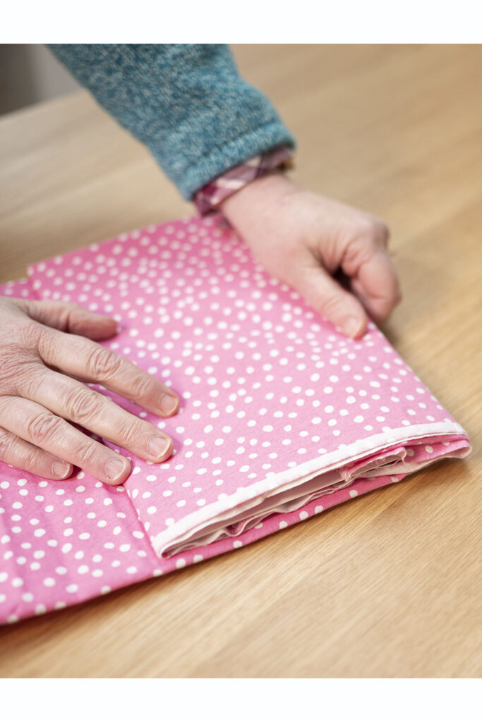 two hands on a cut of pink polka dot fabric