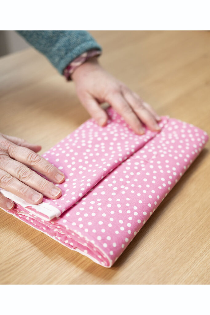 two hands show the last fold of fabric on a mini bolt