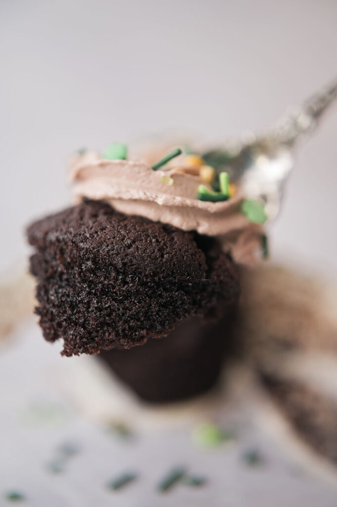 a closeup of a bite of chocolate cake and mocha frosting on the end of a fork