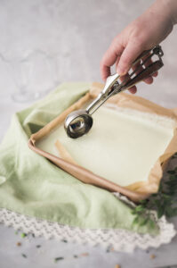 scooping minty green ice cream from a square pan