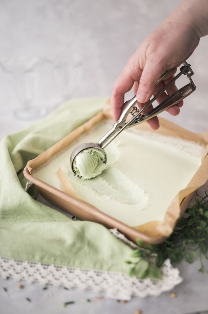 scooping minty green ice cream from a square pan