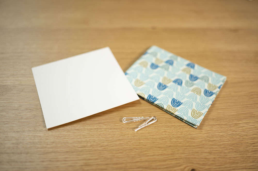 a piece of cardstock, a plastic clip and a small cut of blue rainbow fabric