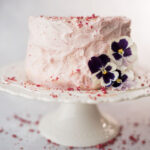 a pink strawberry cake decorated with strawberries and petunias