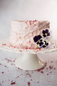 a pink strawberry cake decorated with strawberries and petunias