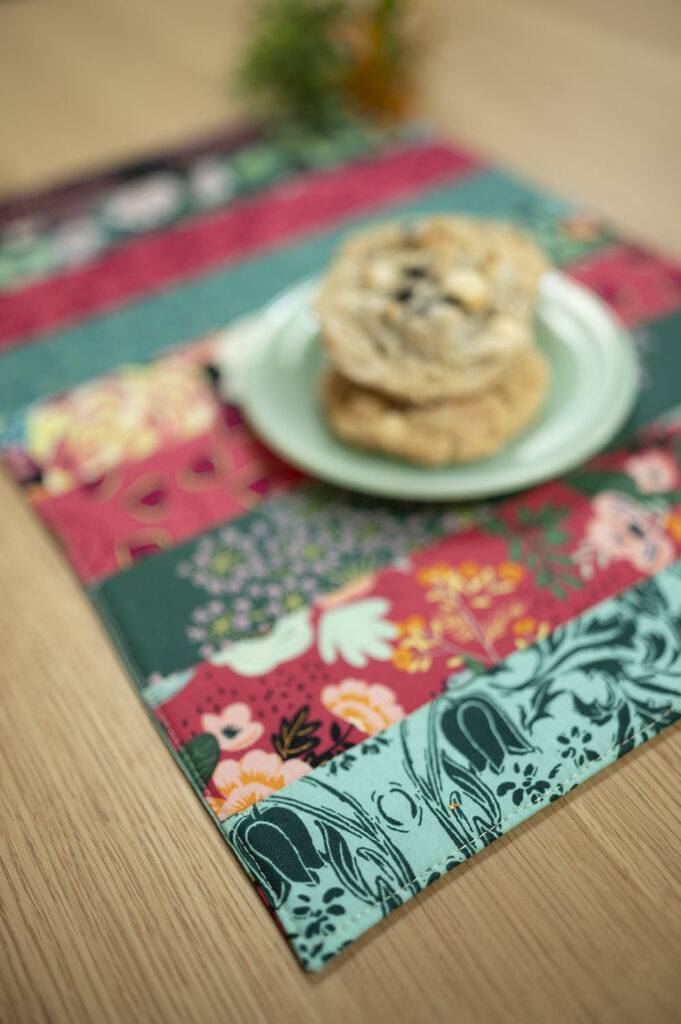colorful strips sewn together to make a placemat shown with a plate of cookies