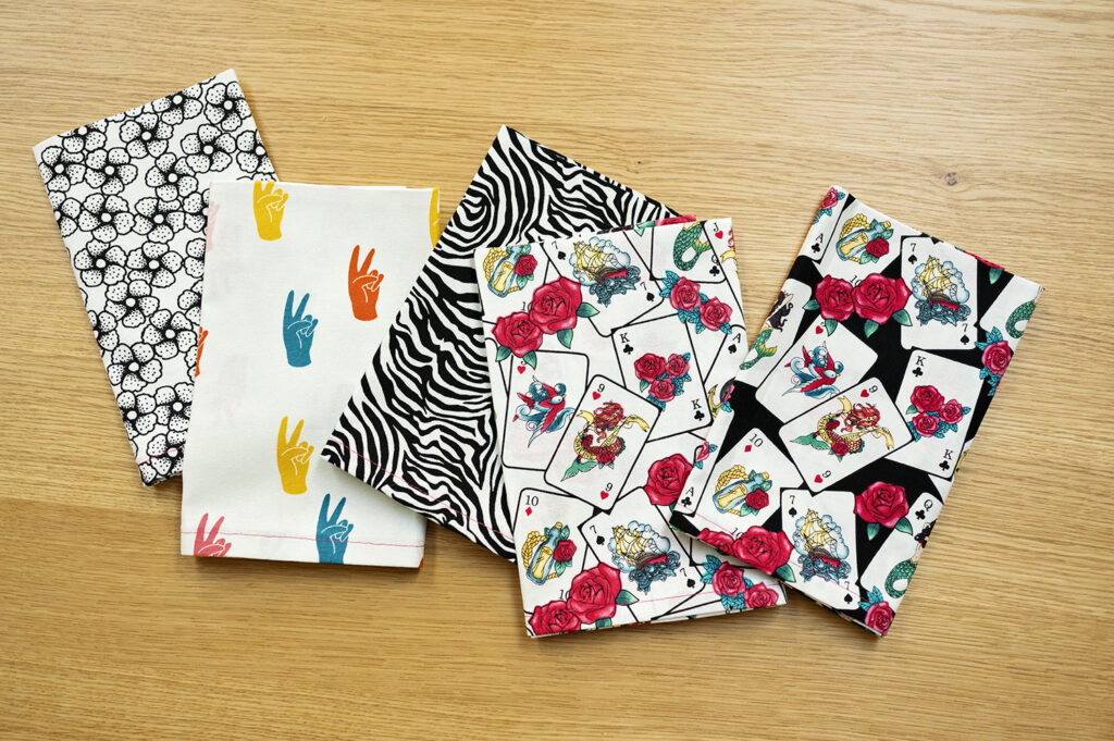 5 neatly folded, brightly printed fabric napkins laid on a wood table top