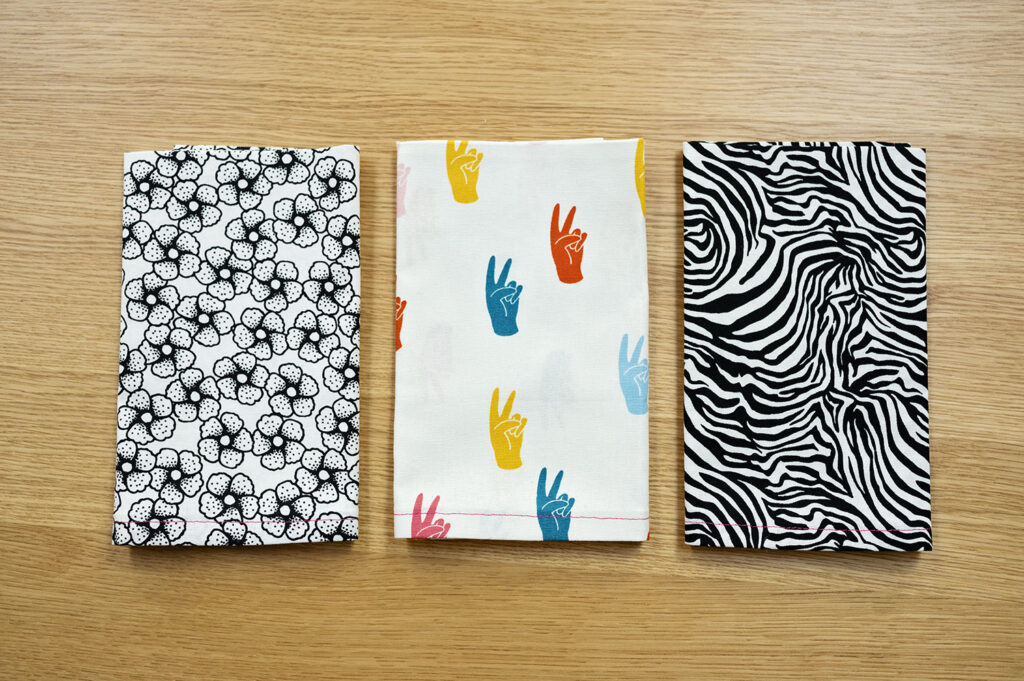 3 boldy printed fabric napkins on a wood table top