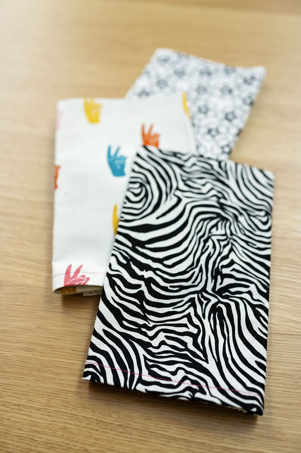 a pile of 3 neatly folded cloth napkins. The one on top is a zebra print