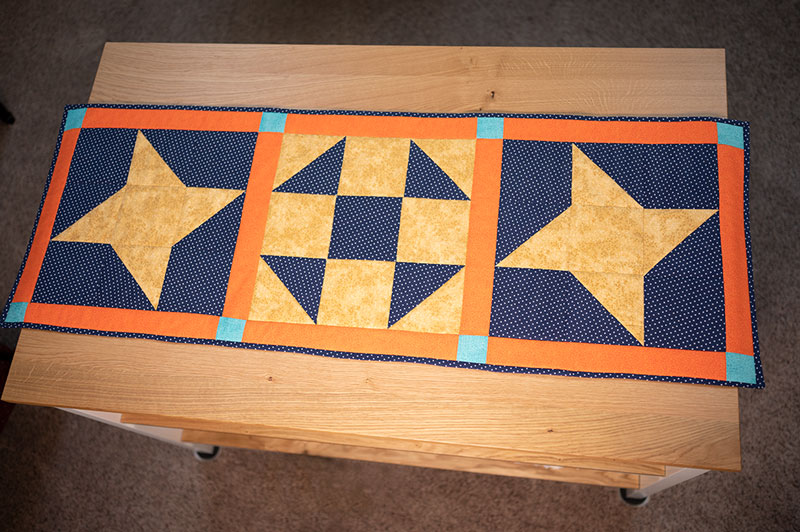 over head view of a quilted table runner made from classic quilt blockssi