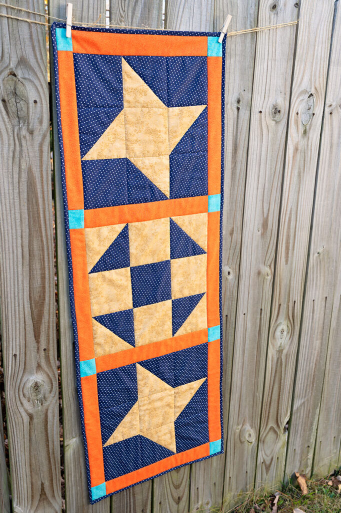 quilted table runner is played on a rustic fence