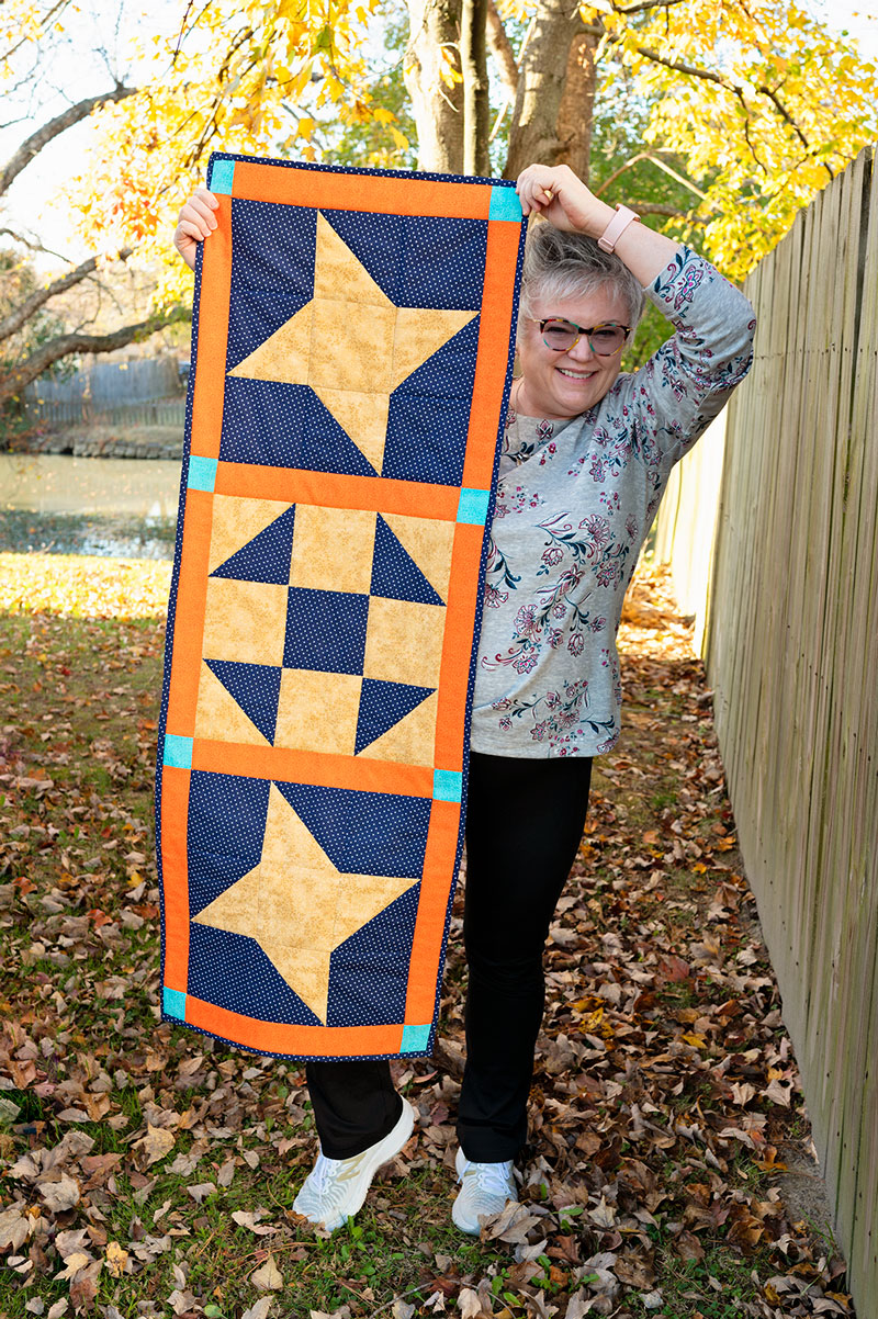 woman holds completed table runner outside