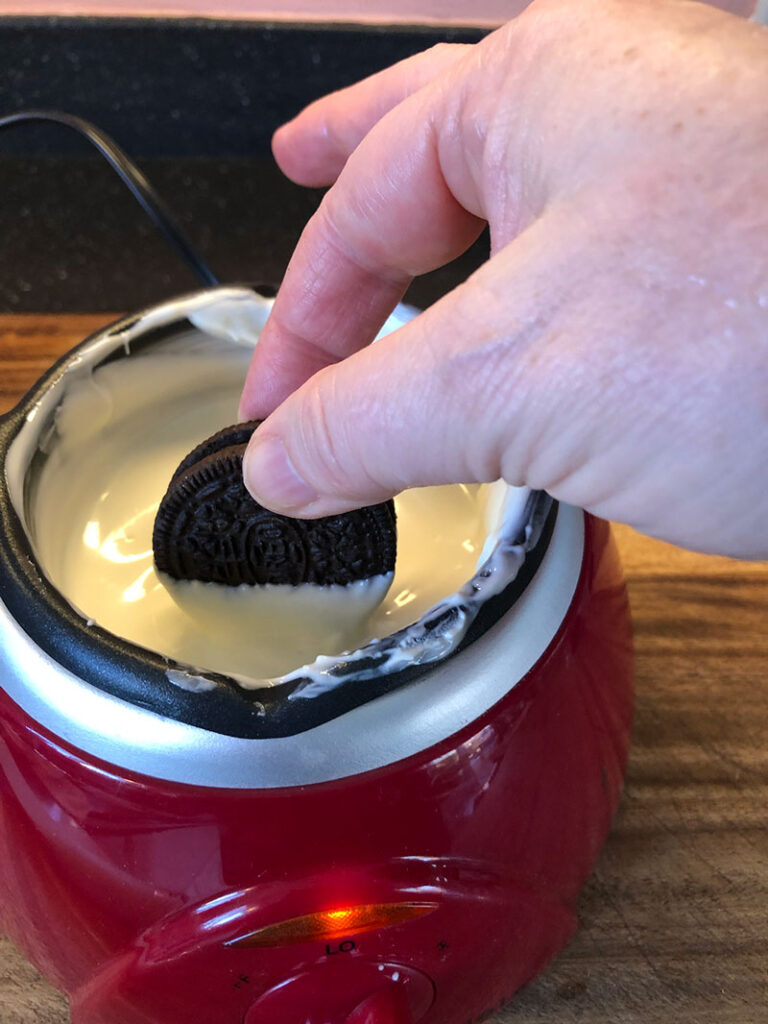 dipping an oreo in melted white chocolate