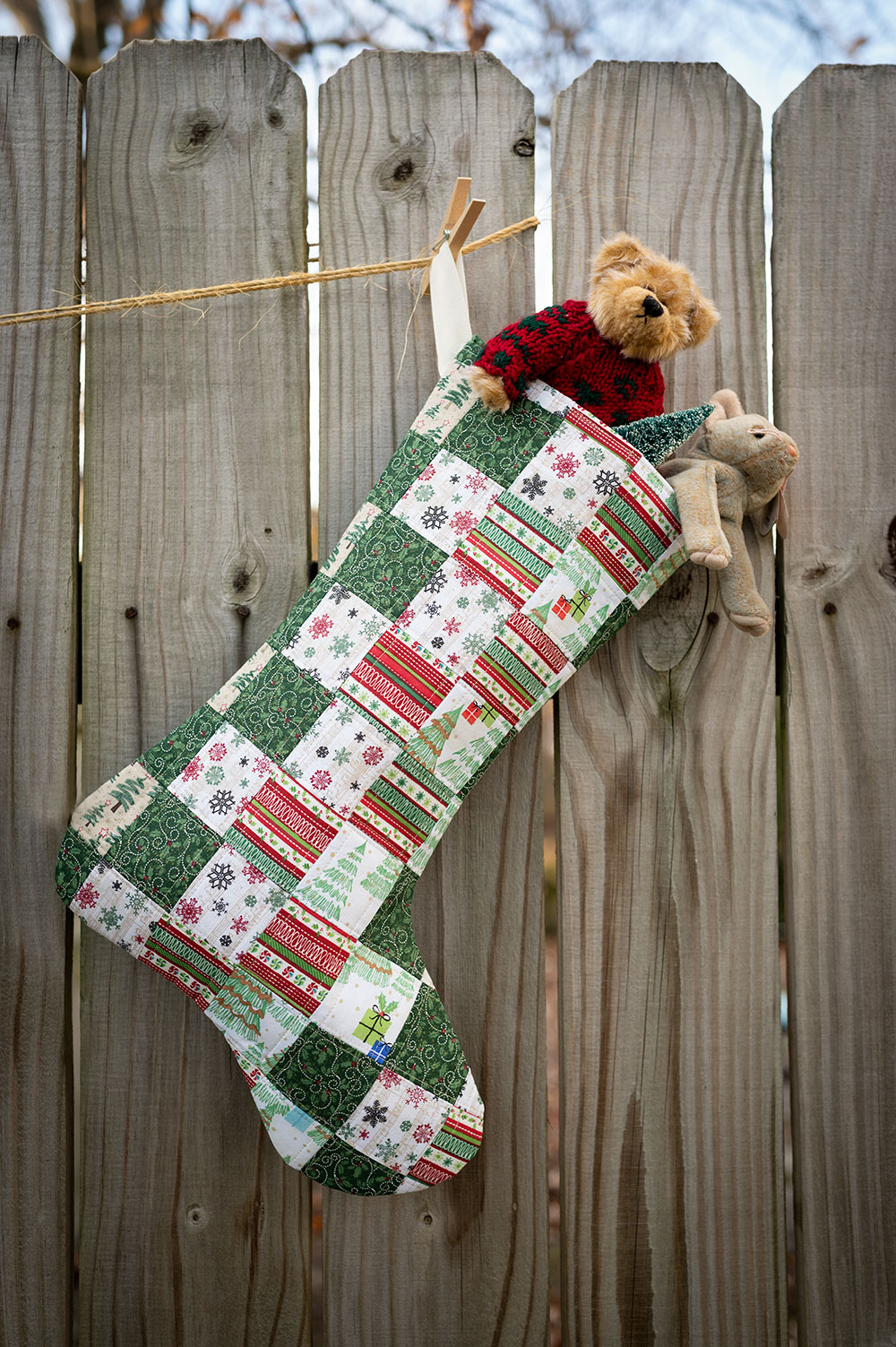 a patchwork quilted Christmas stocking with stuffed animals peeking out at the top