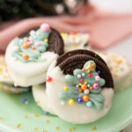 oreo cookies dipped in chocolate and decorated with a piped Christmas tree and sprinkles